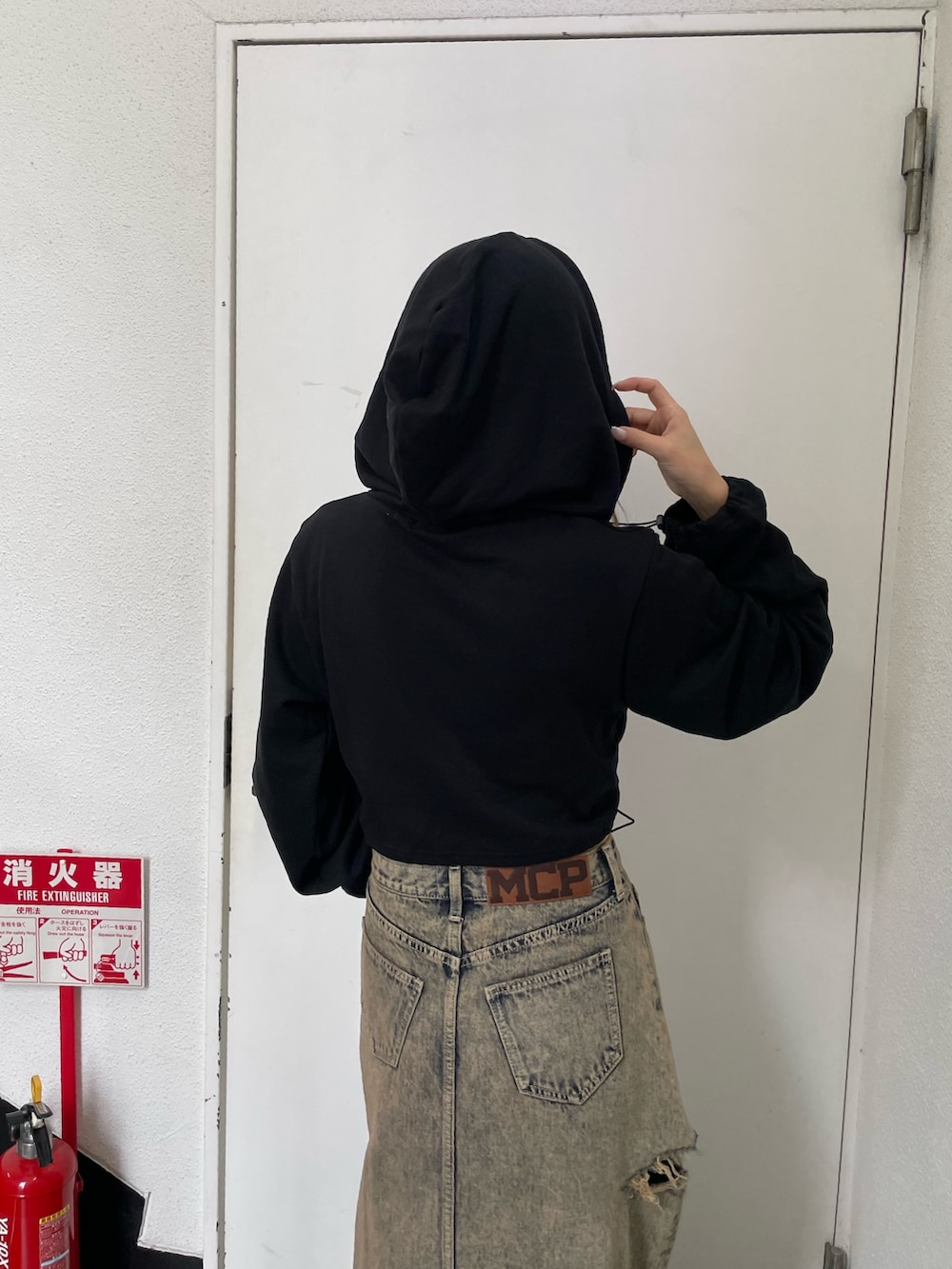 ブラック系のパーカー、ブルー系のデニムスカートを着用したレディースの秋コーディネートの2枚目の写真