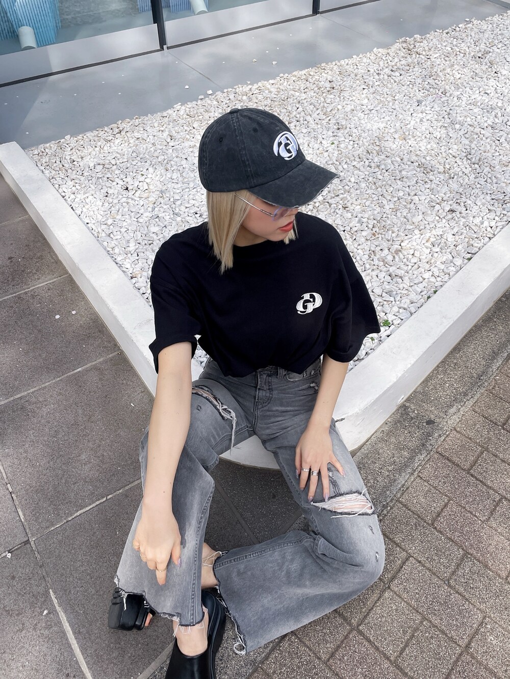 ブラック系のTシャツ/カットソー、グレー系のデニムパンツ、ブラック系のサンダルを着用したレディースの春コーディネートの5枚目の写真