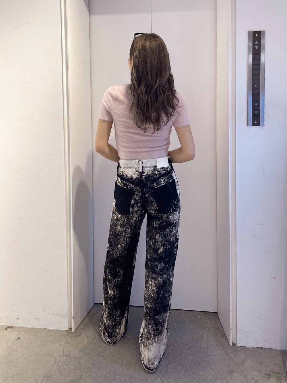 ピンク系のニット/セーター、ブラック系のデニムパンツ、ブラック系のパンプスを着用したレディースの夏コーディネートの2枚目の写真