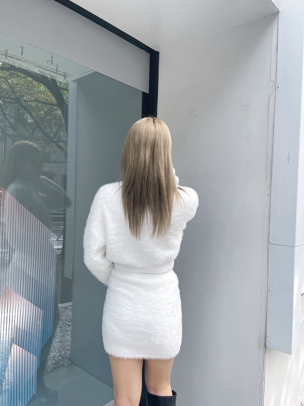 ホワイト系のニット/セーター、ホワイト系のスカート、ブラック系のブーツを着用したレディースの冬コーディネートの5枚目の写真