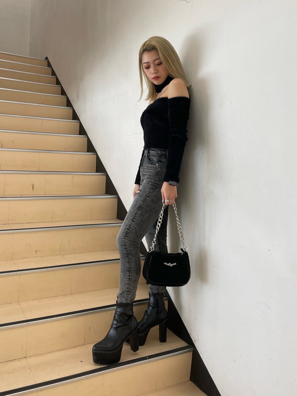 ブラック系のニット/セーター、ブラック系のデニムパンツ、ブラック系のブーツを着用したレディースの秋コーディネートの2枚目の写真