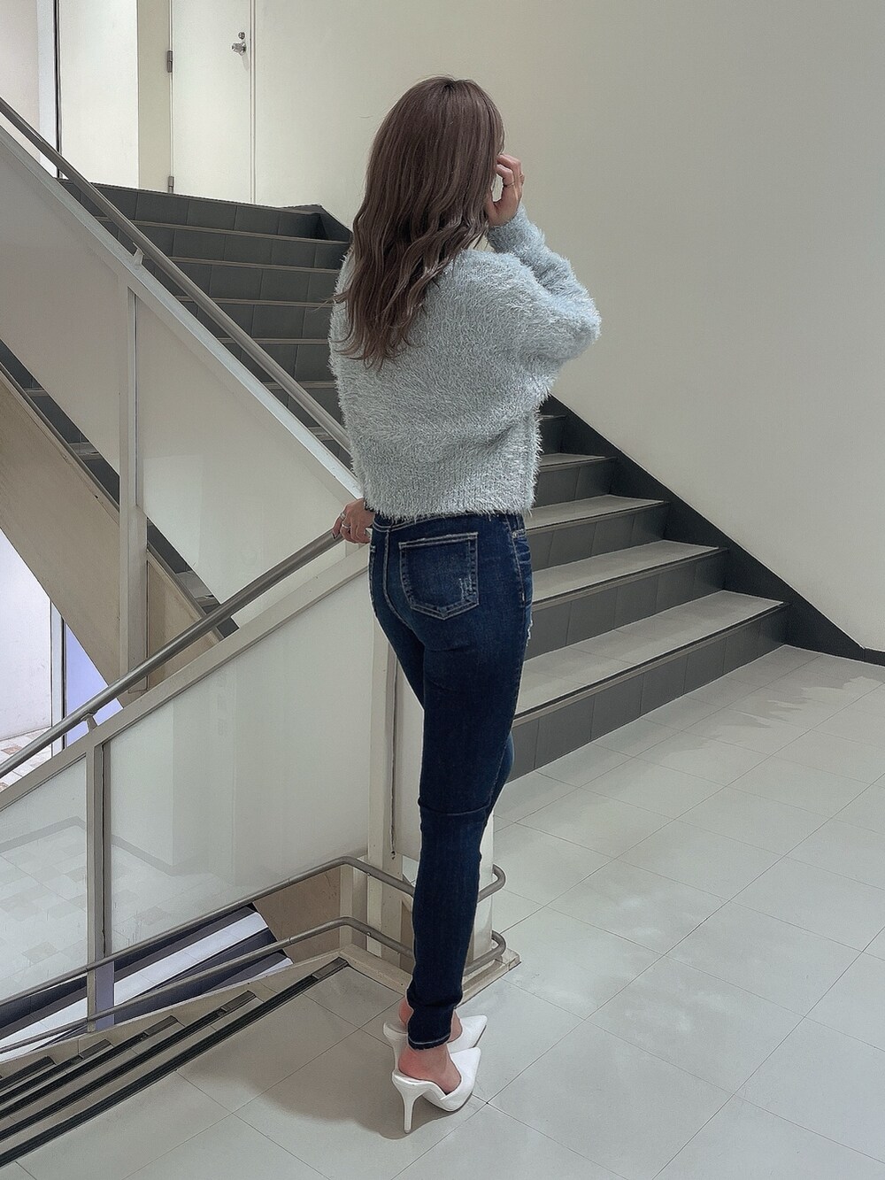 グレー系のニット/セーター、ブルー系のデニムパンツ、ホワイト系のパンプスを着用したレディースの冬コーディネートの4枚目の写真