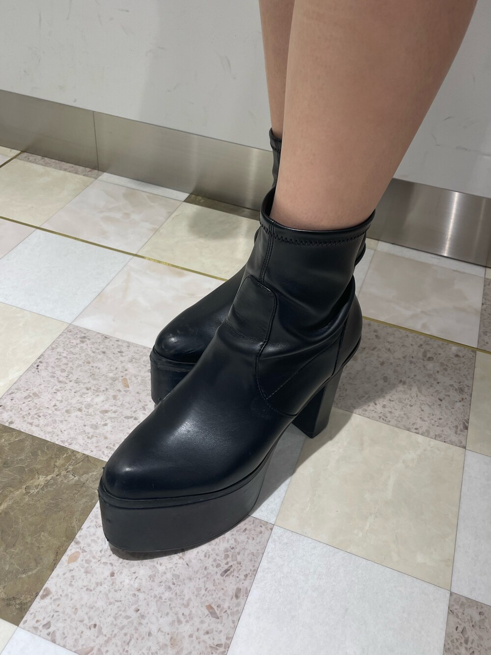 ブラック系のワンピース、ブラック系のブーツ、ホワイト系のダウンジャケット/コートを着用したレディースの冬コーディネートの9枚目の写真