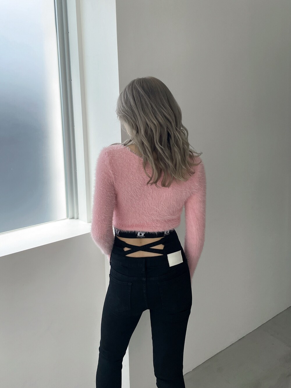 ピンク系のニット/セーター、ブラック系のデニムパンツ、ブラック系のパンプスを着用したレディースの冬コーディネートの5枚目の写真