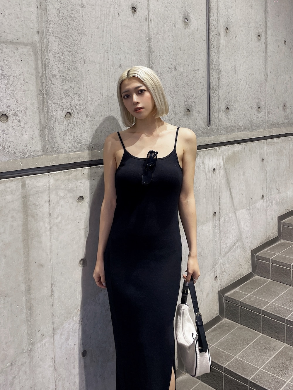 ホワイト系のハンドバッグ、ブラック系のワンピース、ホワイト系のサンダルを着用したレディースの夏コーディネートの3枚目の写真