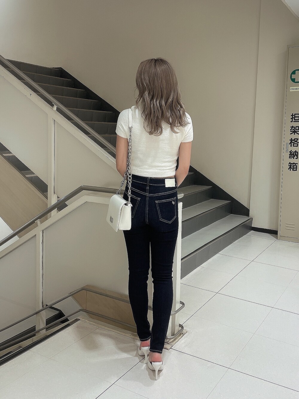 ホワイト系のニット/セーター、ブルー系のデニムパンツ、ホワイト系のパンプスを着用したレディースの夏コーディネートの2枚目の写真