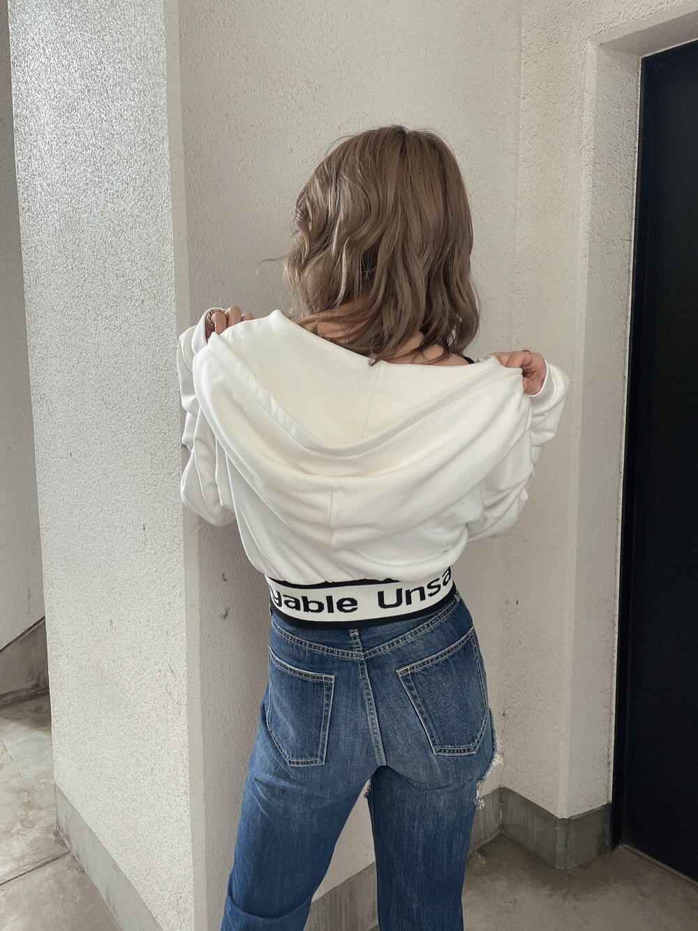 ホワイト系のパーカー、ブルー系のデニムパンツ、ホワイト系のパンプスを着用したレディースの春コーディネートの5枚目の写真