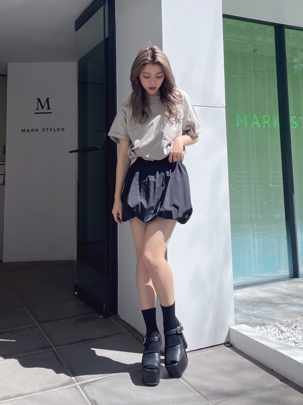ベージュ系のTシャツ/カットソー、ブラック系のスカート、ブラック系のサンダルを着用したレディースの春コーディネートの2枚目の写真