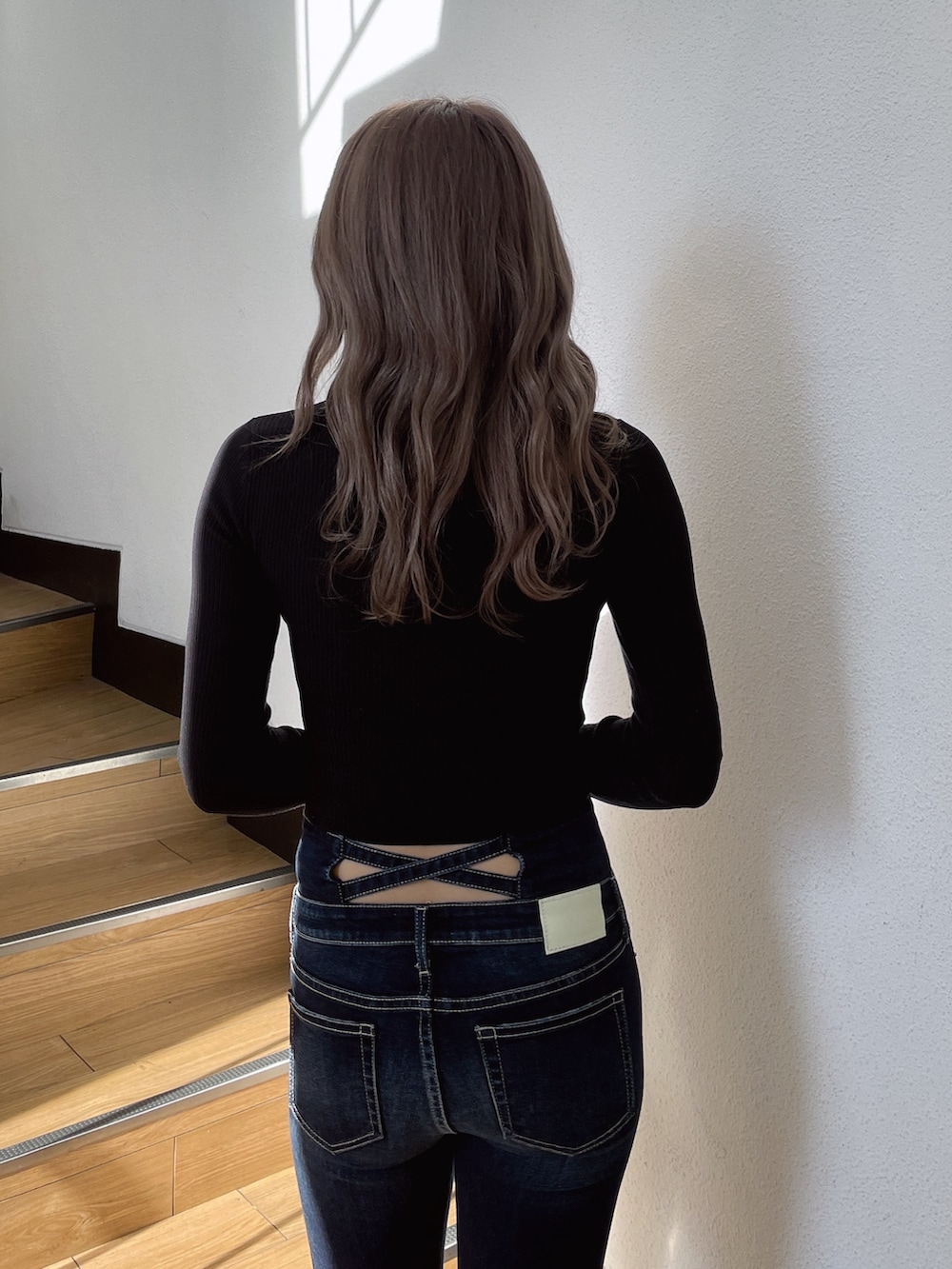 ブラック系のニット/セーター、ブラック系のパンプス、ブルー系のデニムパンツを着用したレディースの冬コーディネートの3枚目の写真