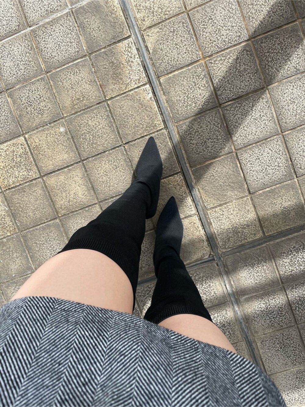 ブラック系のライダースジャケット、ホワイト系のニット/セーター、ブラック系のスカートを着用したレディースの秋コーディネートの8枚目の写真