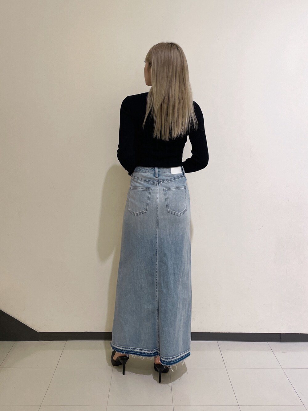 ブラック系のニット/セーター、ブルー系のデニムスカート、ブラック系のパンプスを着用したレディースの秋コーディネートの3枚目の写真