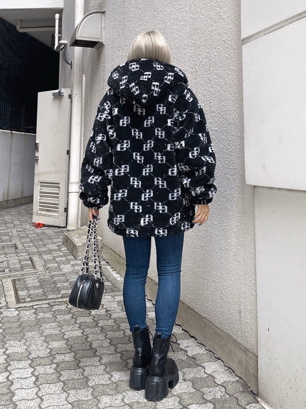 ブラック系のブルゾン、ブラック系のニット/セーター、ブルー系のデニムパンツを着用したレディースの秋コーディネートの2枚目の写真