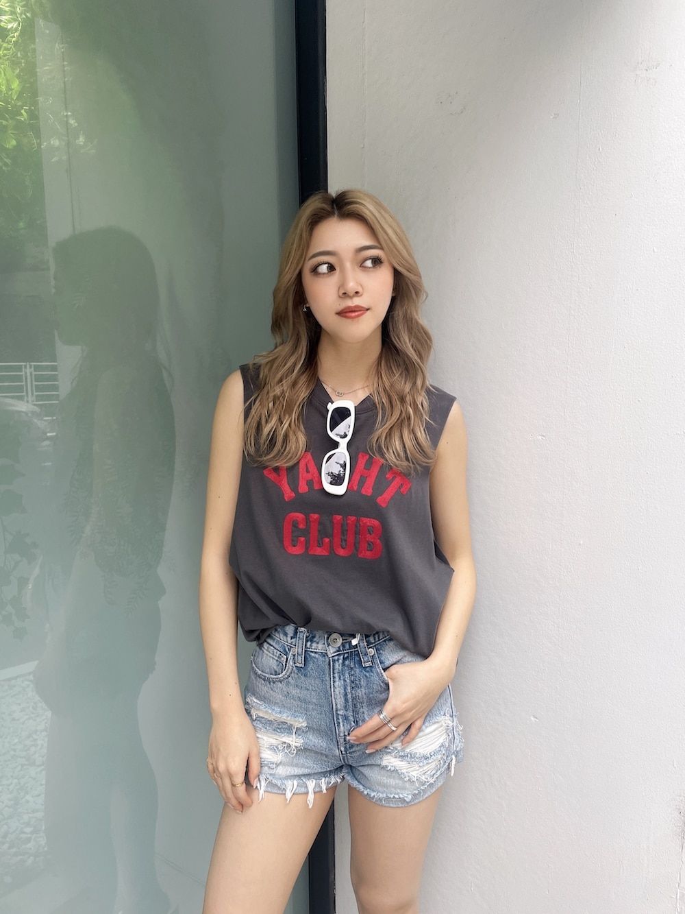 グレー系のタンクトップ、ブルー系のデニムパンツ、ホワイト系のサンダルを着用したレディースの夏コーディネートの3枚目の写真