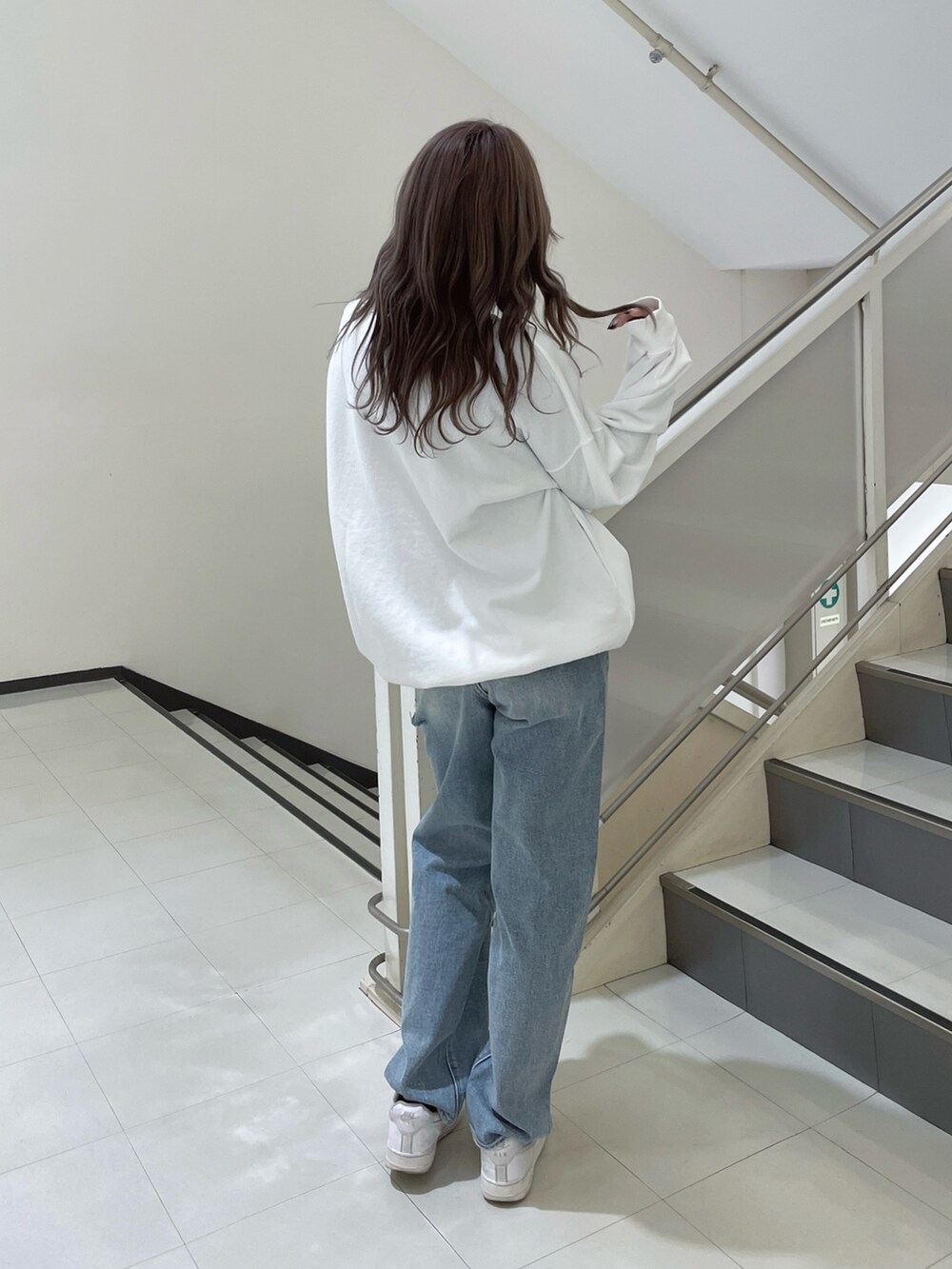 ホワイト系のスウェット、ブルー系のデニムパンツを着用したレディースの冬コーディネートの2枚目の写真