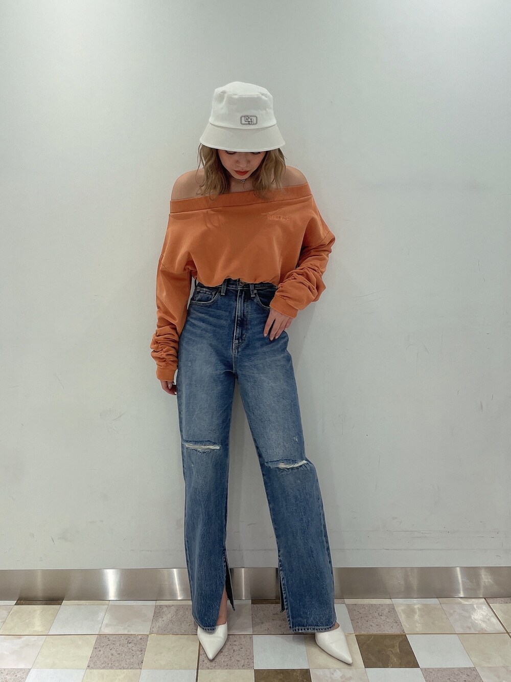 オレンジ系のTシャツ/カットソー、ブルー系のデニムパンツ、ホワイト系のパンプスを着用したレディースの冬コーディネートの2枚目の写真