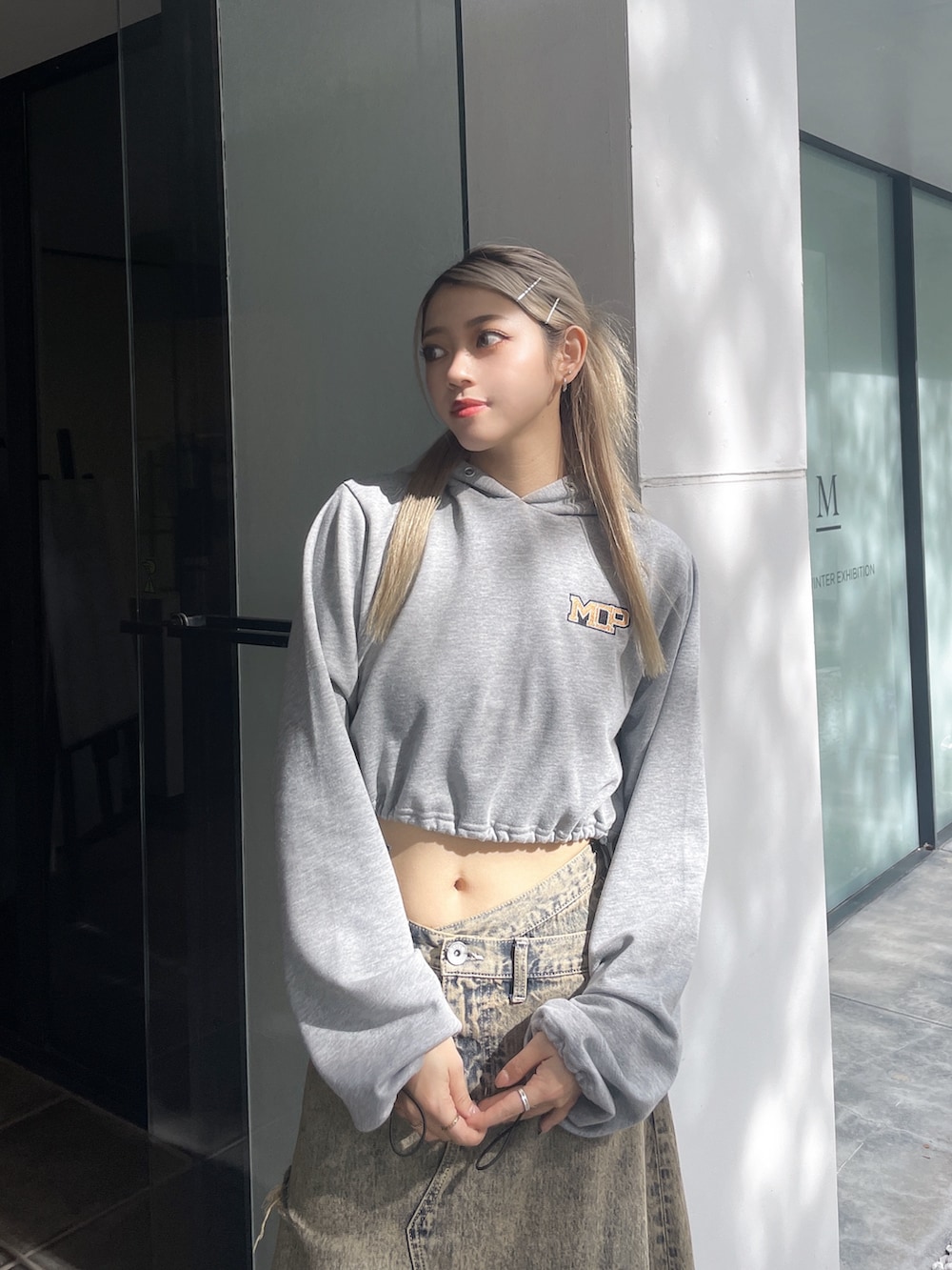 グレー系のパーカー、ブルー系のデニムスカート、ブラック系のパンプスを着用したレディースの秋コーディネートの3枚目の写真