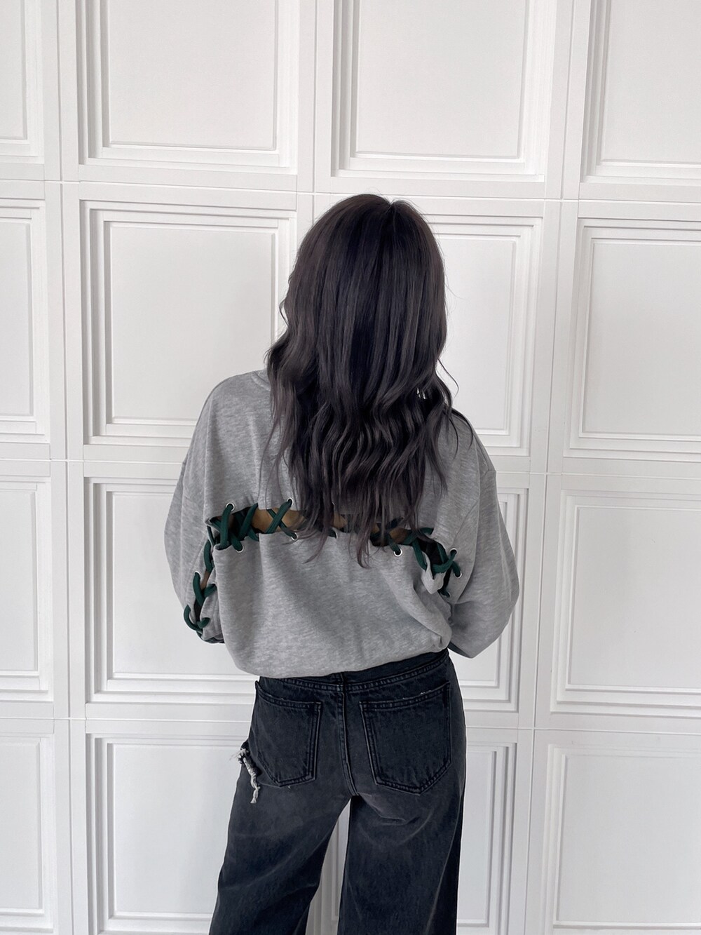 グレー系のスウェット、ブラック系のデニムパンツ、ブラック系のブーツを着用したレディースの秋コーディネートの4枚目の写真