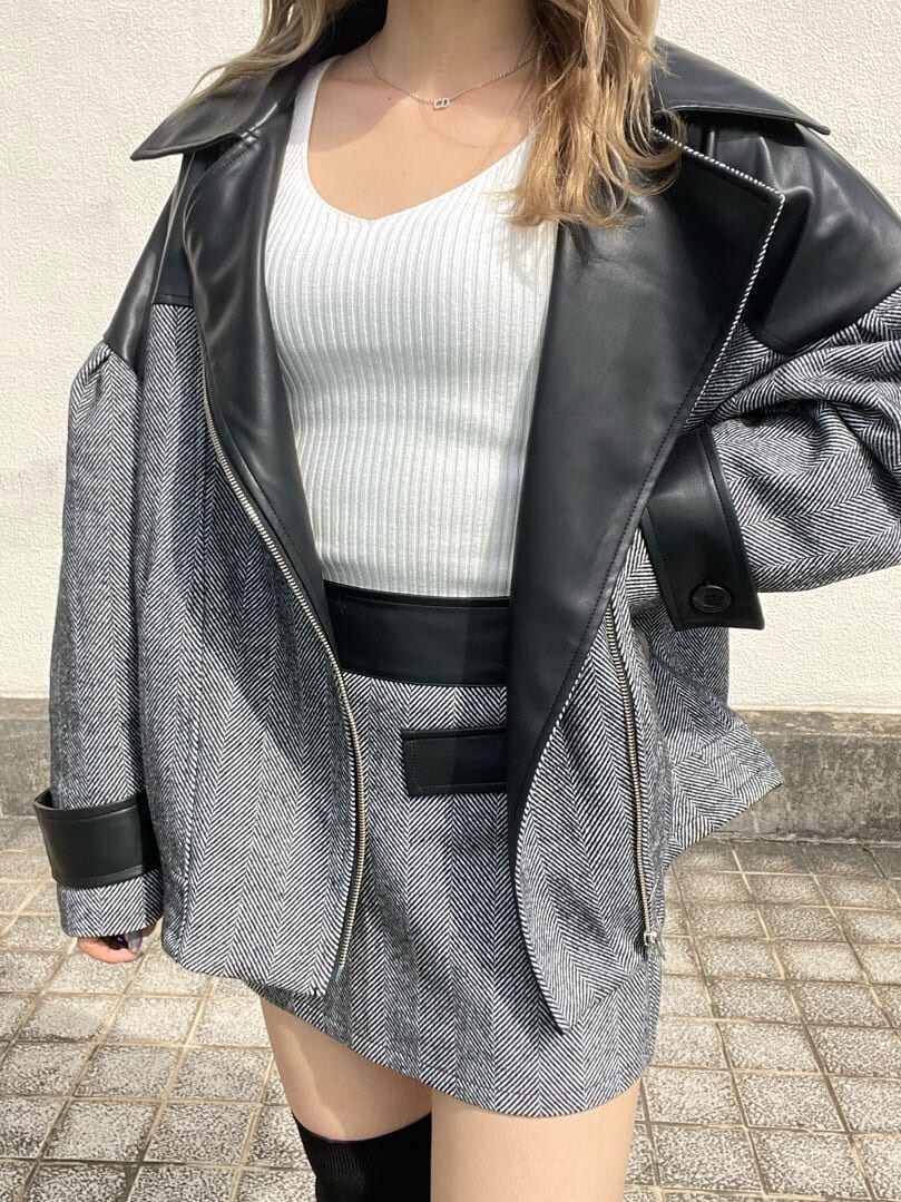 ブラック系のライダースジャケット、ホワイト系のニット/セーター、ブラック系のスカートを着用したレディースの秋コーディネートの4枚目の写真