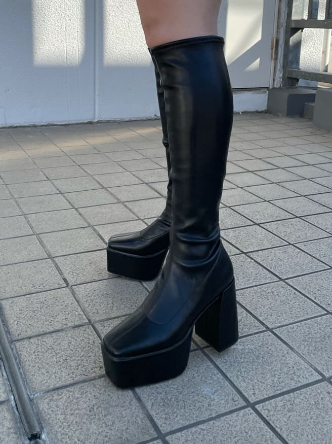 グレー系のニット/セーター、ブラック系のスカート、ブラック系のブーツを着用したレディースの秋コーディネートの7枚目の写真