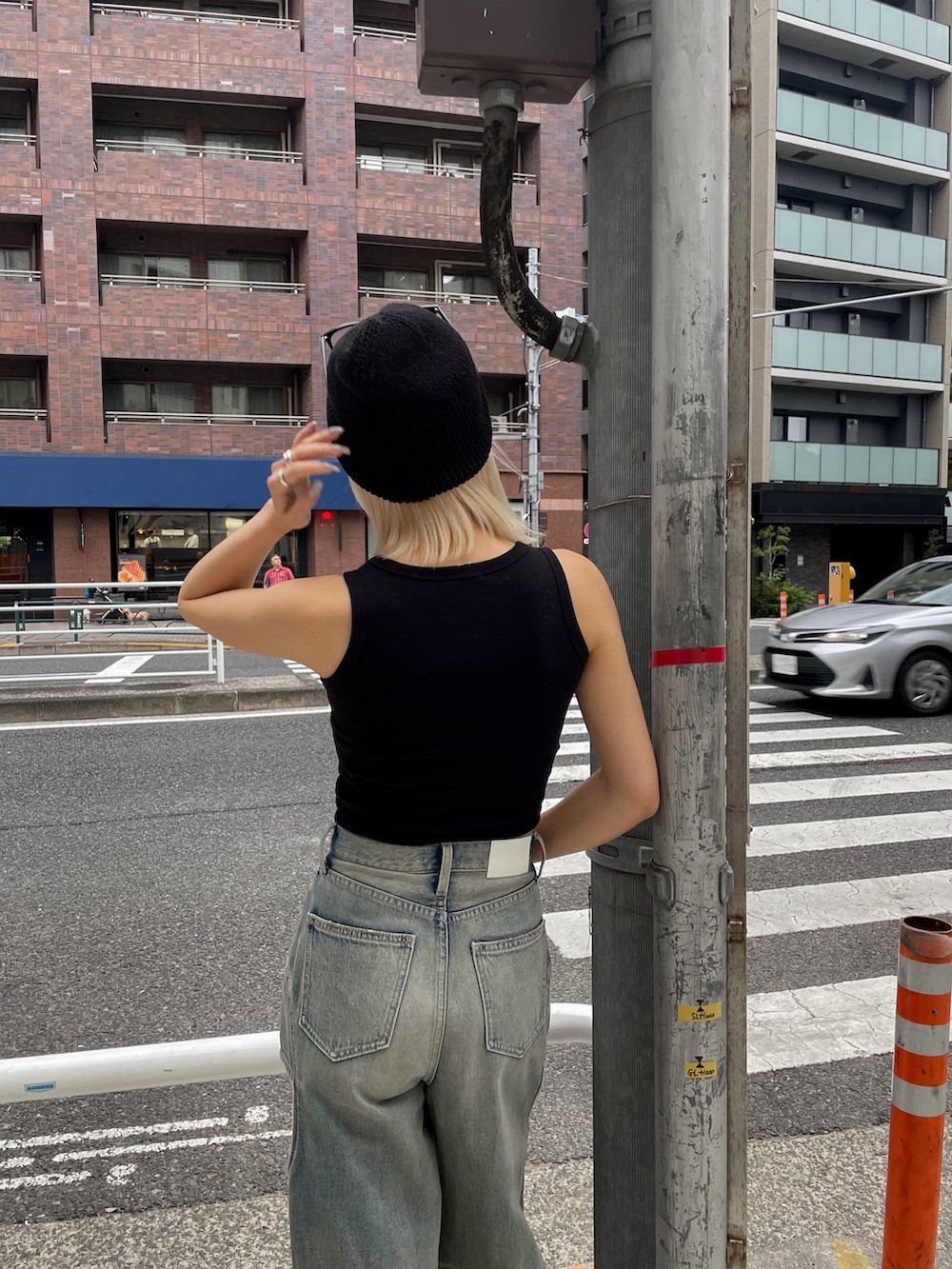 ブラック系のタンクトップ、ブルー系のデニムパンツ、ブラック系のハンドバッグを着用したレディースの春コーディネートの3枚目の写真