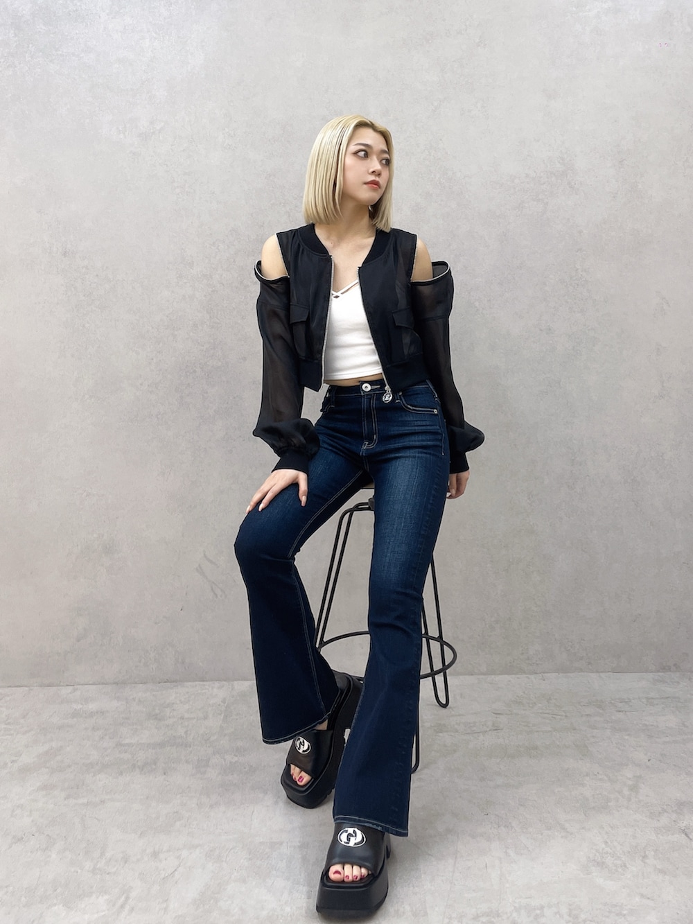 ブルー系のデニムパンツ、ホワイト系のキャミソール、ブラック系のブルゾンを着用したレディースの春コーディネートの2枚目の写真