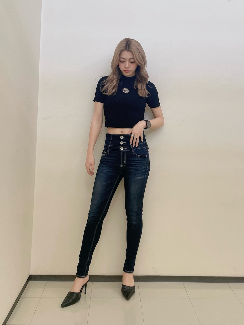 ブラック系のニット/セーター、ブルー系のデニムパンツ、ブラック系のパンプスを着用したレディースの春コーディネートの2枚目の写真
