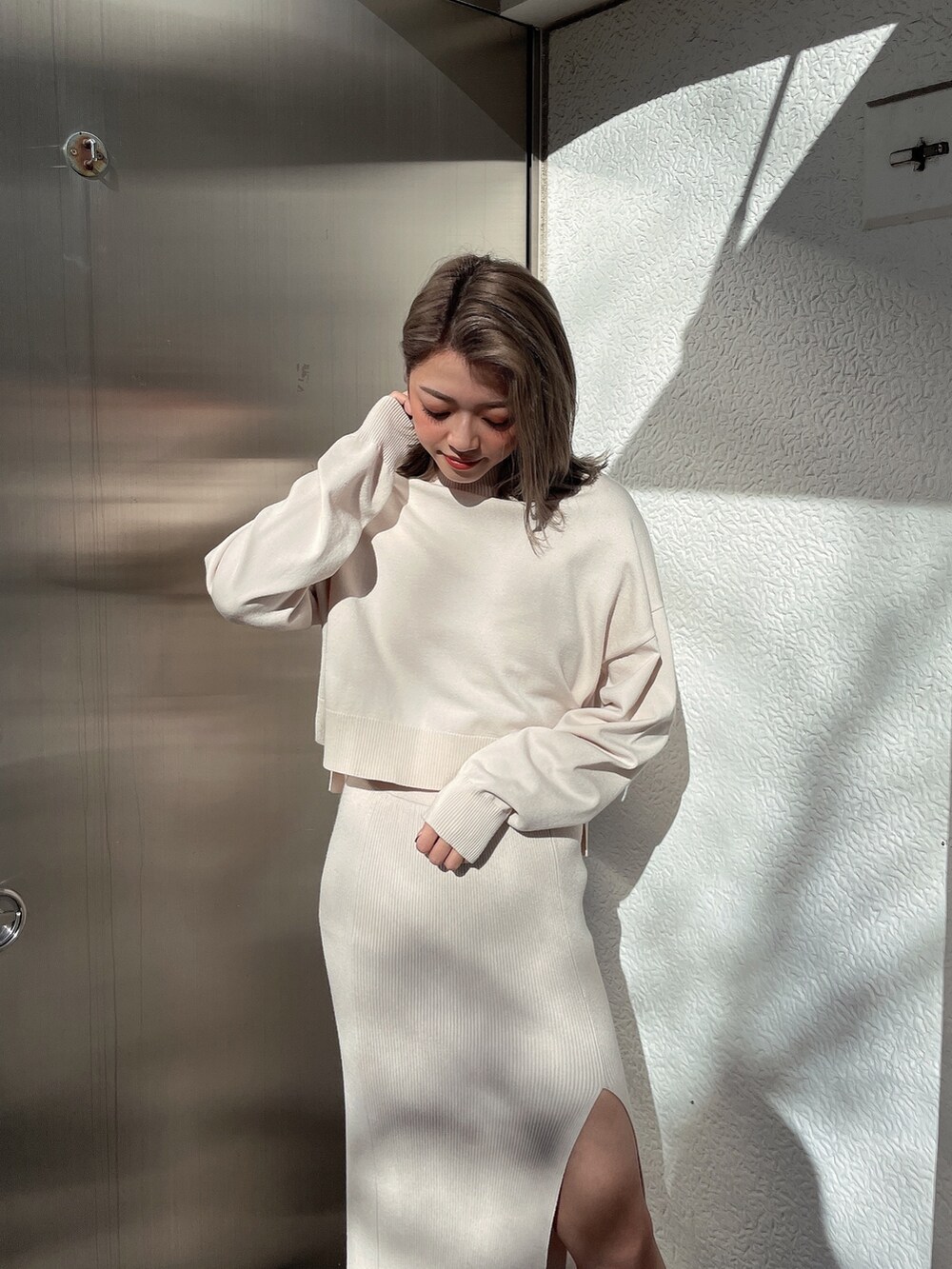 ホワイト系のニット/セーター、ホワイト系のスカート、ブラック系のブーツを着用したレディースの冬コーディネートの4枚目の写真