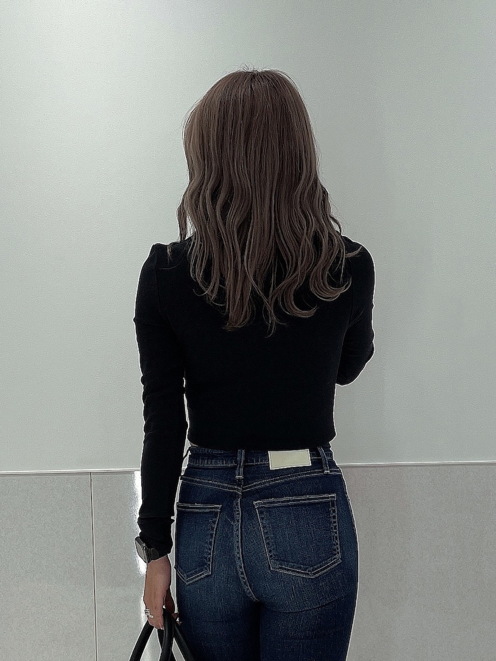 ブルー系のデニムパンツ、ブラック系のブーツ、ブラック系のボストンバッグを着用したレディースの秋コーディネートの5枚目の写真