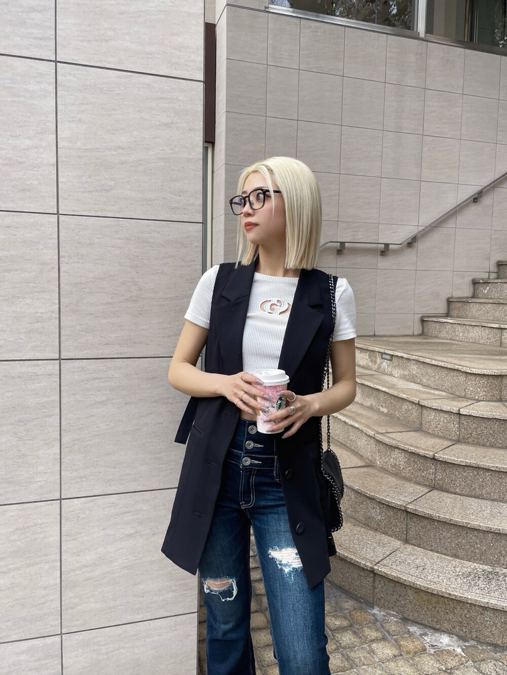 ブラック系のベスト、ホワイト系のTシャツ/カットソー、ブルー系のデニムパンツを着用したレディースの春コーディネートの3枚目の写真