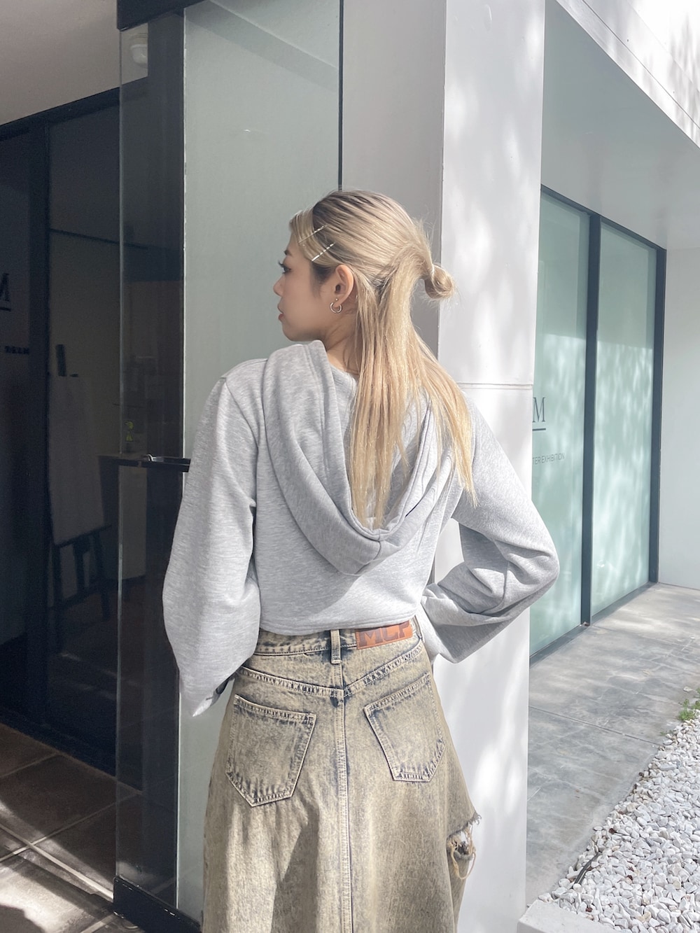 グレー系のパーカー、ブルー系のデニムスカート、ブラック系のパンプスを着用したレディースの秋コーディネートの5枚目の写真