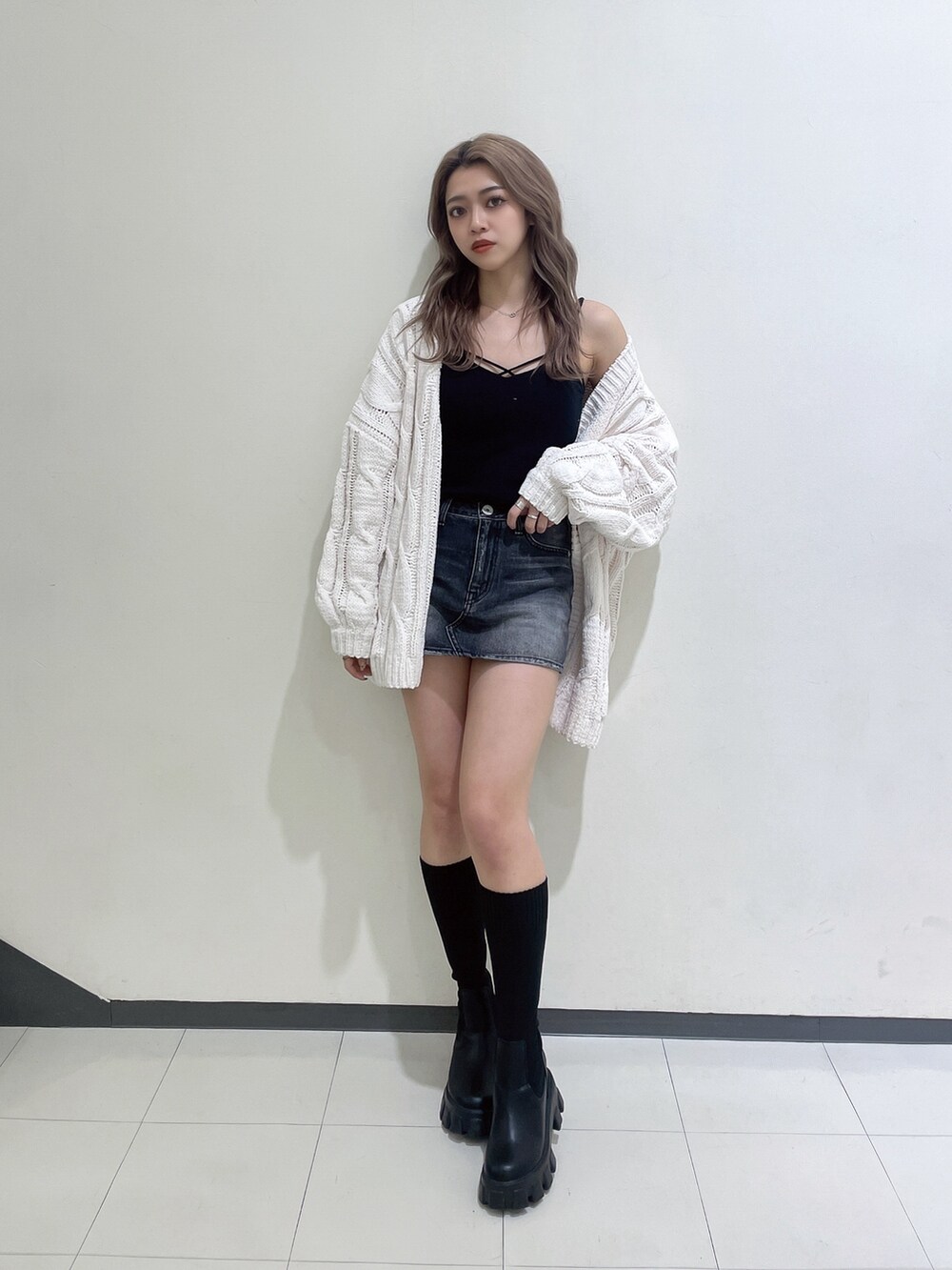 ホワイト系のカーディガン/ボレロ、ブラック系のデニムスカート、ブラック系のブーツを着用したレディースの冬コーディネートの2枚目の写真