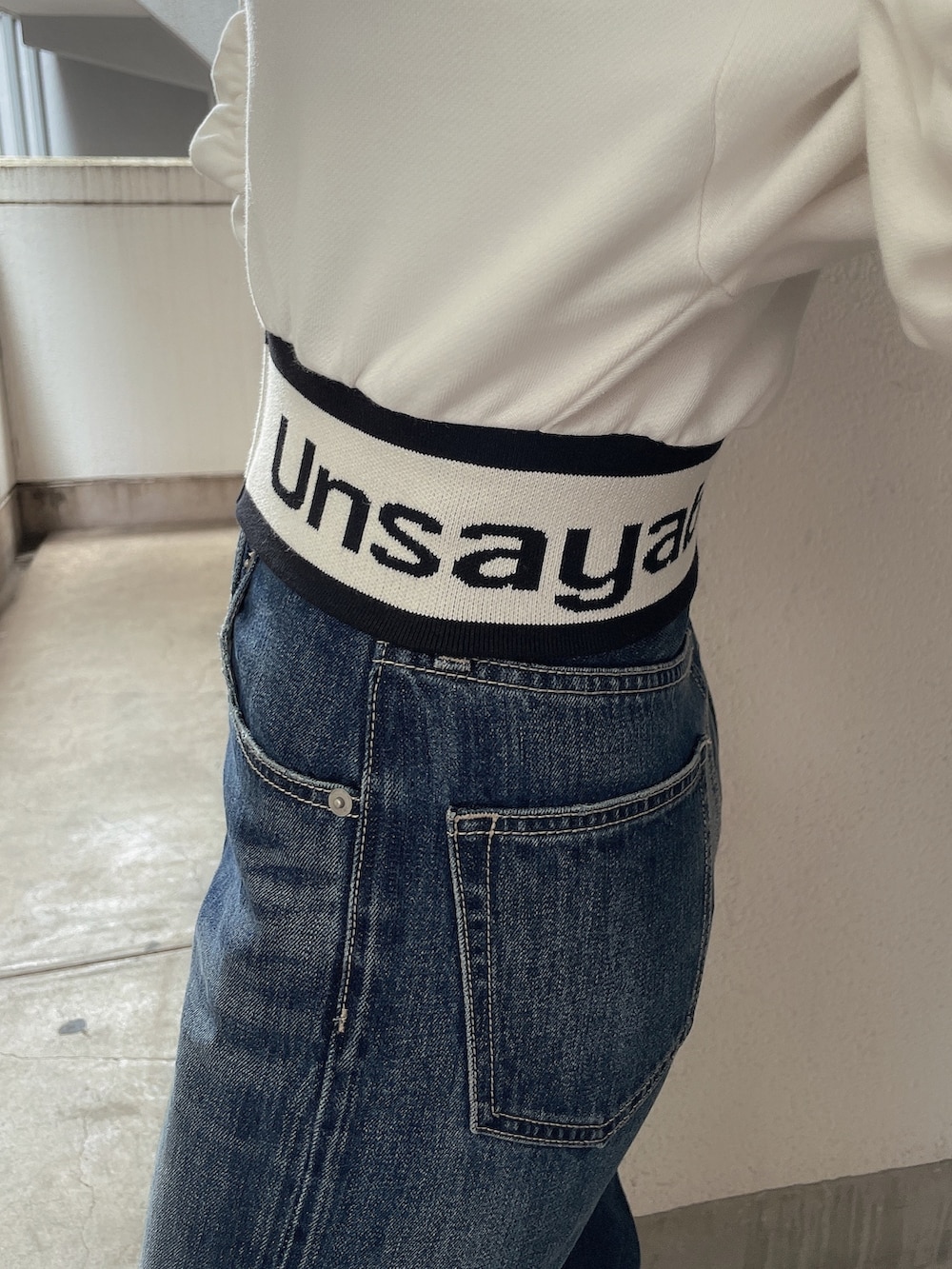 ホワイト系のパーカー、ブルー系のデニムパンツ、ホワイト系のパンプスを着用したレディースの春コーディネートの6枚目の写真