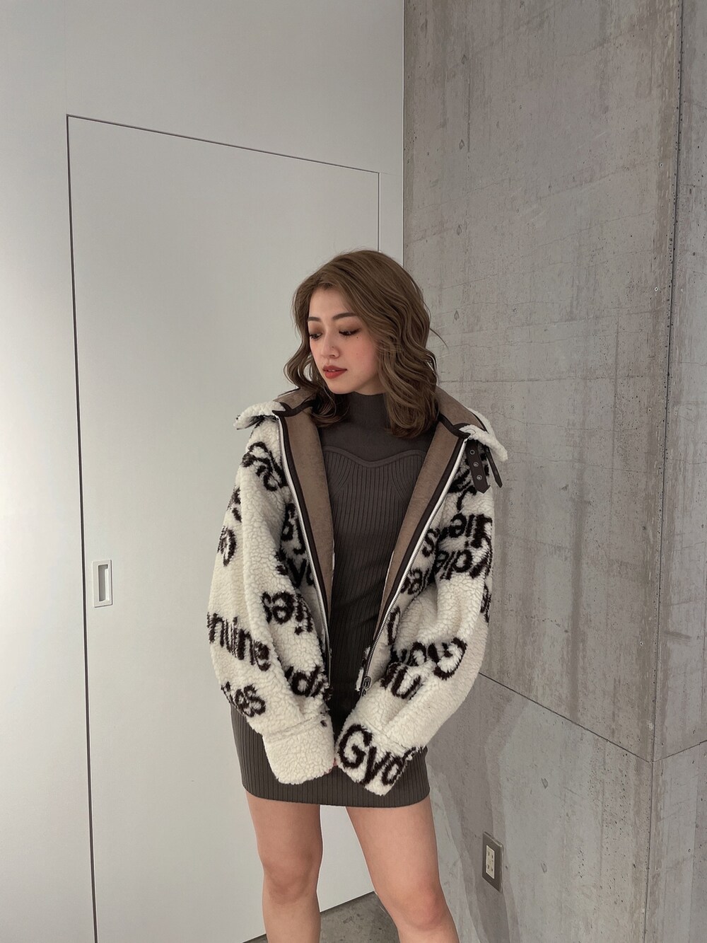 ホワイト系のブルゾン、グリーン系のワンピース、ブラック系のブーツを着用したレディースの冬コーディネートの5枚目の写真