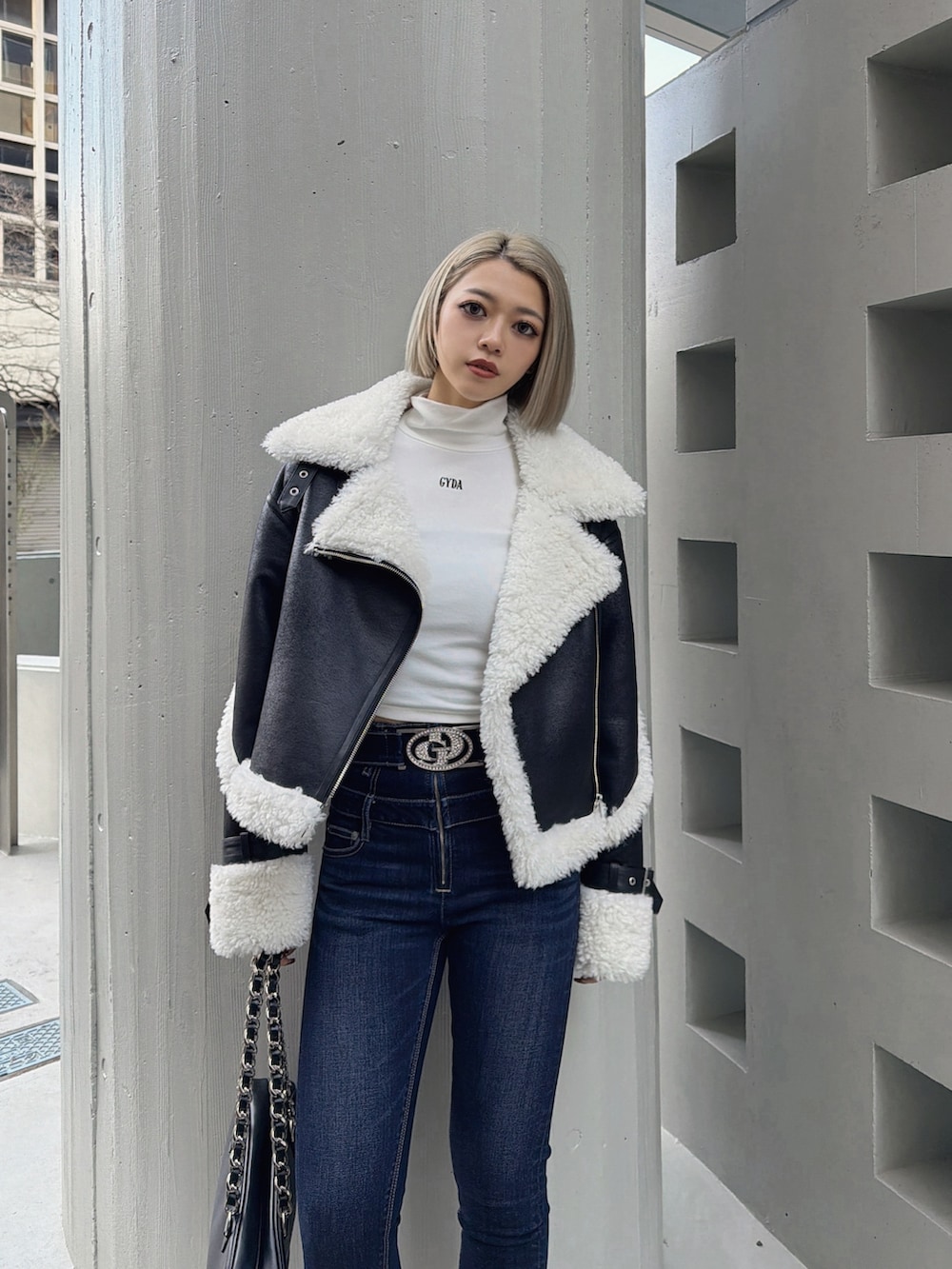 ブラック系のムートンコート、ホワイト系のTシャツ/カットソー、ブルー系のデニムパンツを着用したレディースの冬コーディネートの3枚目の写真