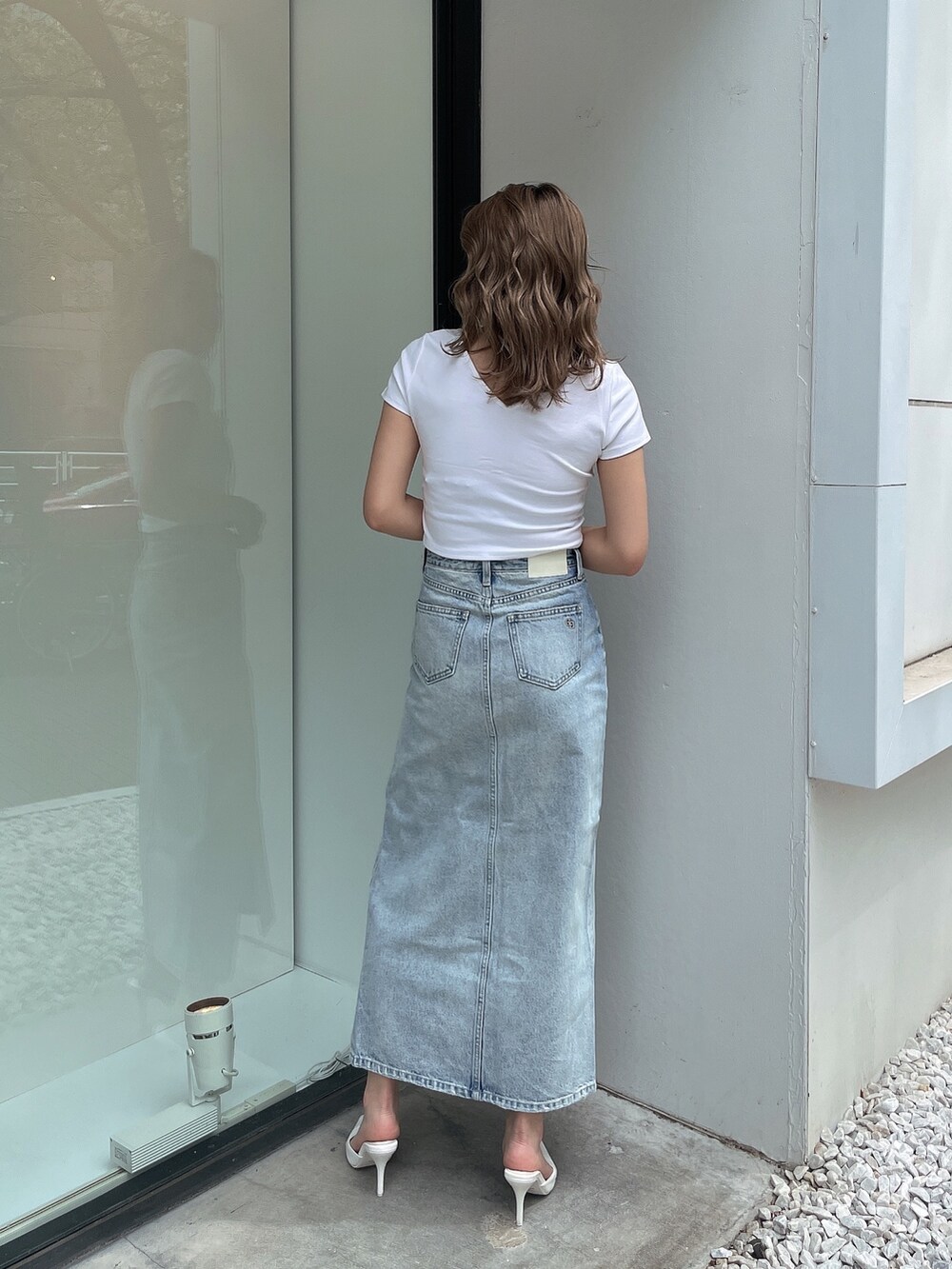 ブルー系のデニムスカート、ホワイト系のTシャツ/カットソー、ホワイト系のパンプスを着用したレディースの春コーディネートの3枚目の写真