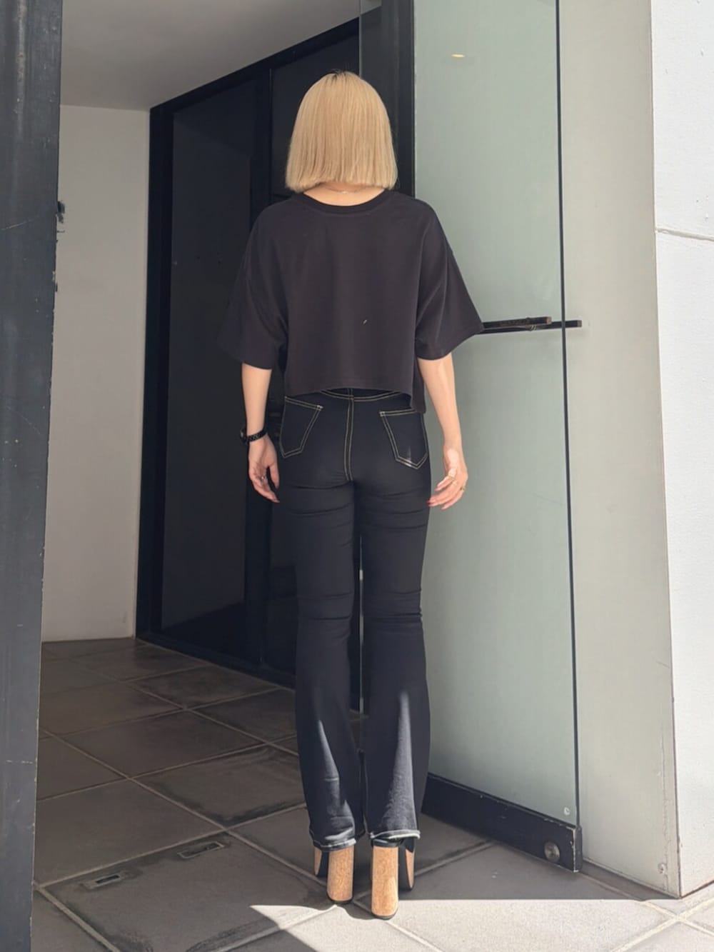ブラック系のサンダル、ブラック系のTシャツ/カットソー、ブラック系のデニムパンツを着用したレディースの夏コーディネートの3枚目の写真