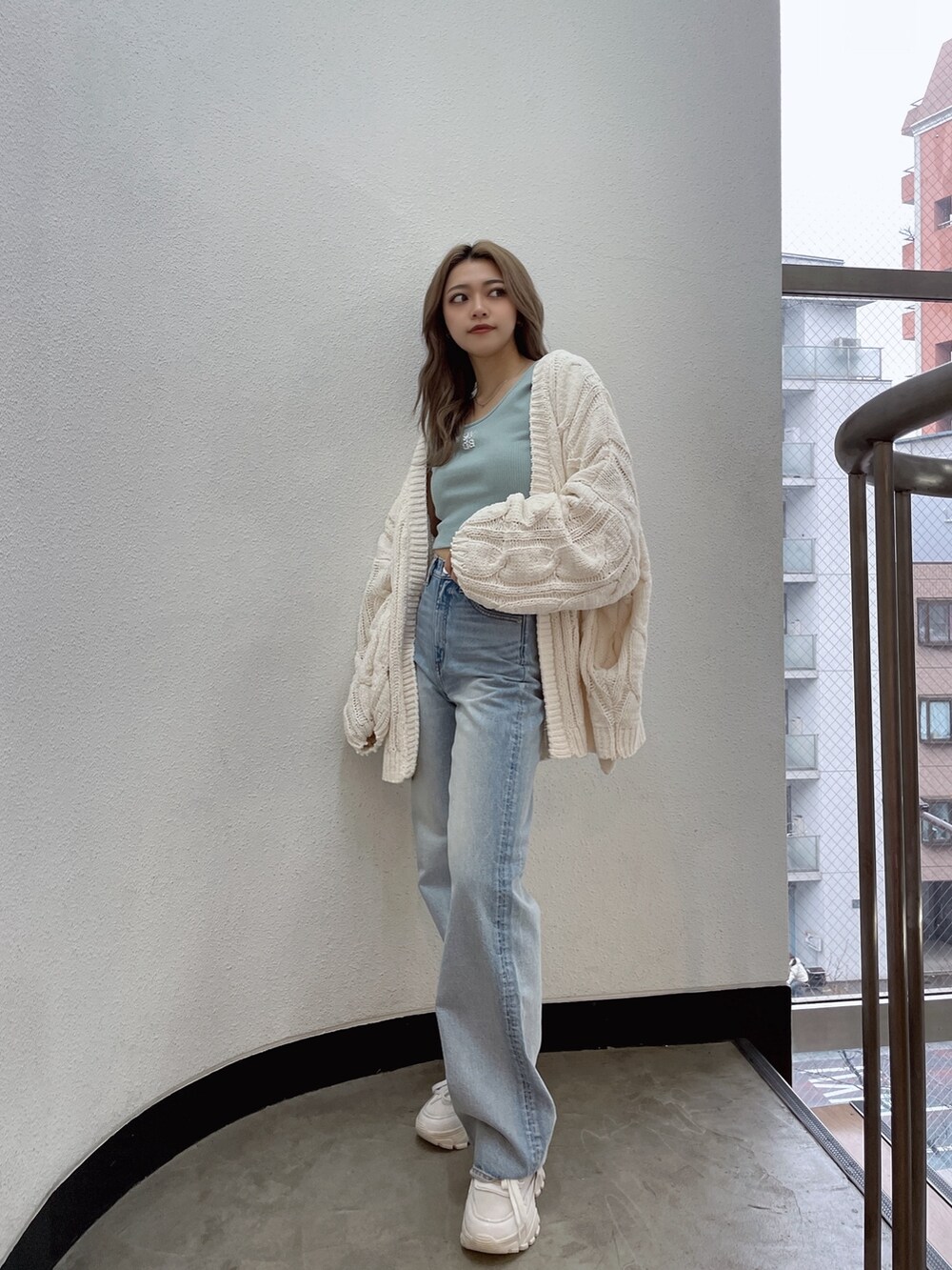 ホワイト系のカーディガン/ボレロ、グリーン系のTシャツ/カットソー、ブルー系のデニムパンツを着用したレディースの冬コーディネートの3枚目の写真