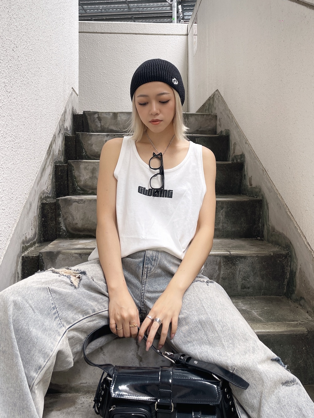 ホワイト系のワンピース、ブルー系のデニムパンツ、ブラック系のスニーカーを着用したレディースの夏コーディネートの2枚目の写真