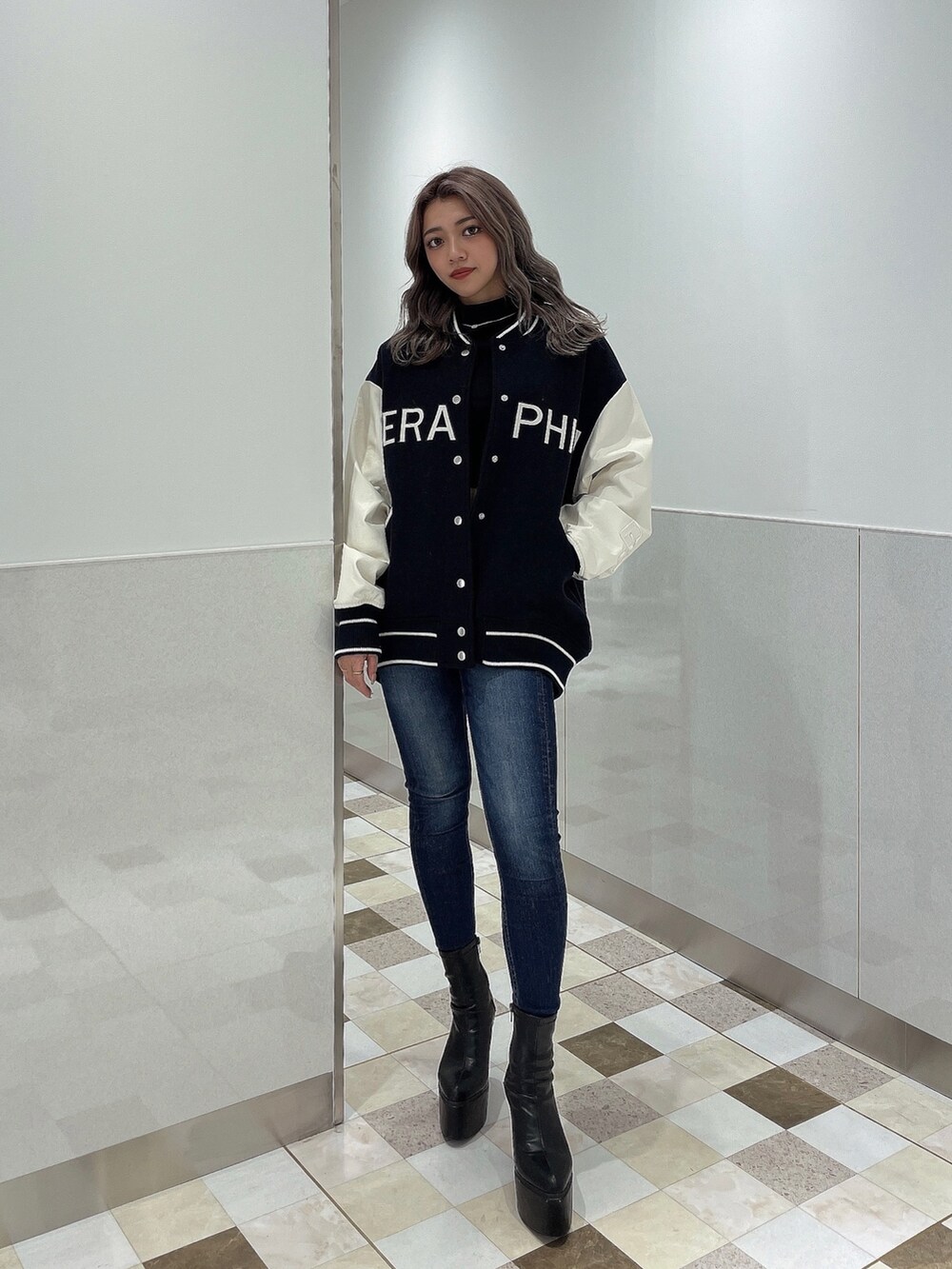 ブルー系のスタジャン、ブルー系のデニムパンツ、ブラック系のブーツを着用したレディースの秋コーディネートの3枚目の写真