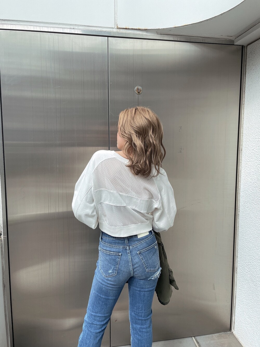 その他のミリタリージャケット、ブルー系のデニムパンツ、ホワイト系のスウェットを着用したレディースの春コーディネートの5枚目の写真