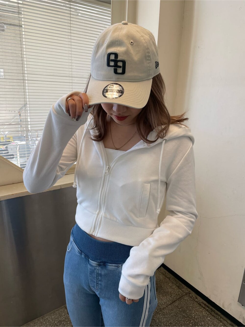 ホワイト系のパーカー、ホワイト系のパンプス、ブルー系のデニムパンツを着用したレディースの冬コーディネートの2枚目の写真