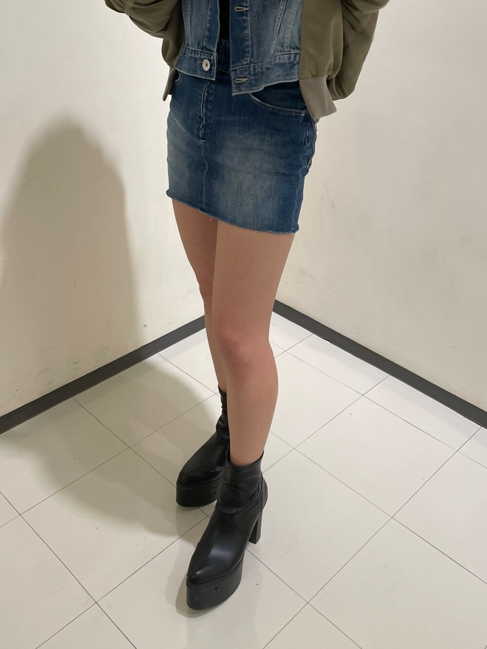 ブルー系のデニムスカート、ブラック系のブーツ、ブラック系のTシャツ/カットソーを着用したレディースの冬コーディネートの9枚目の写真