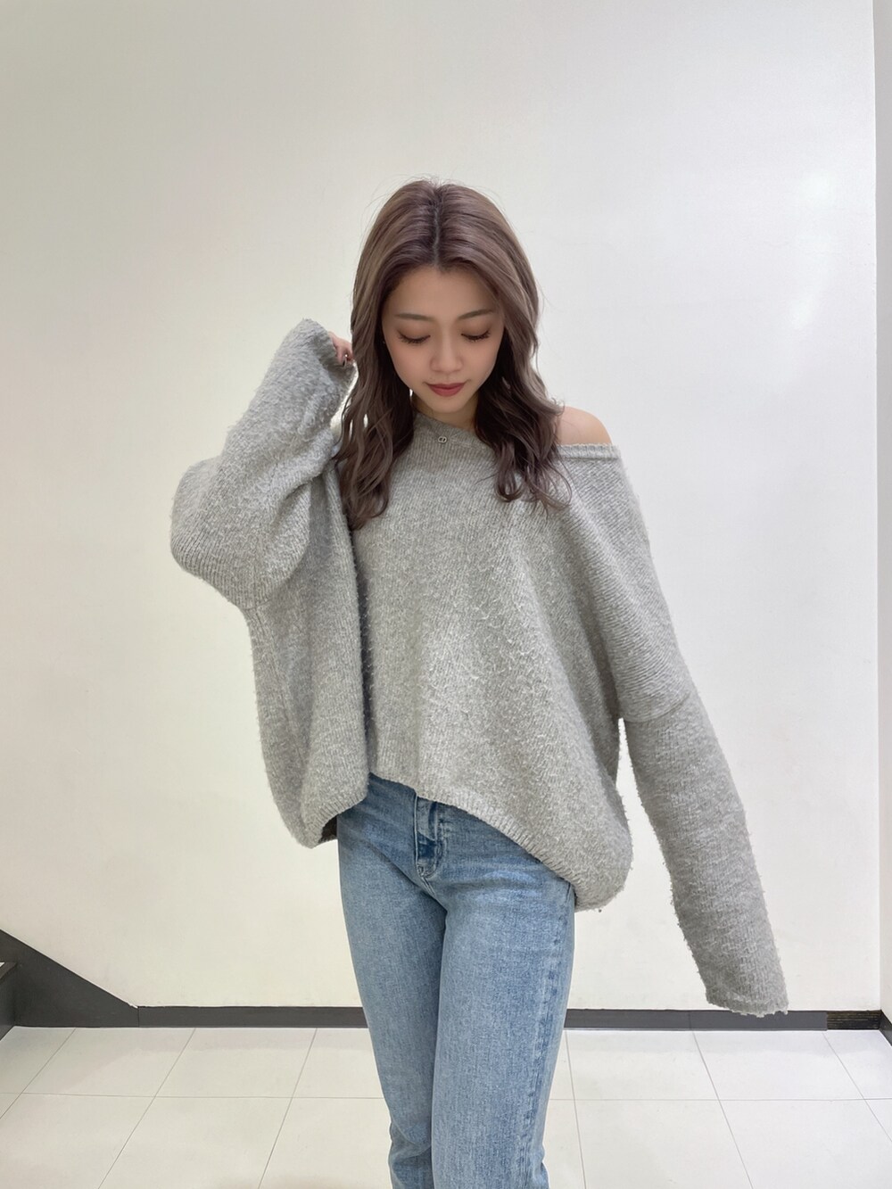 グレー系のニット/セーター、ブルー系のデニムパンツ、ホワイト系のパンプスを着用したレディースの冬コーディネートの4枚目の写真