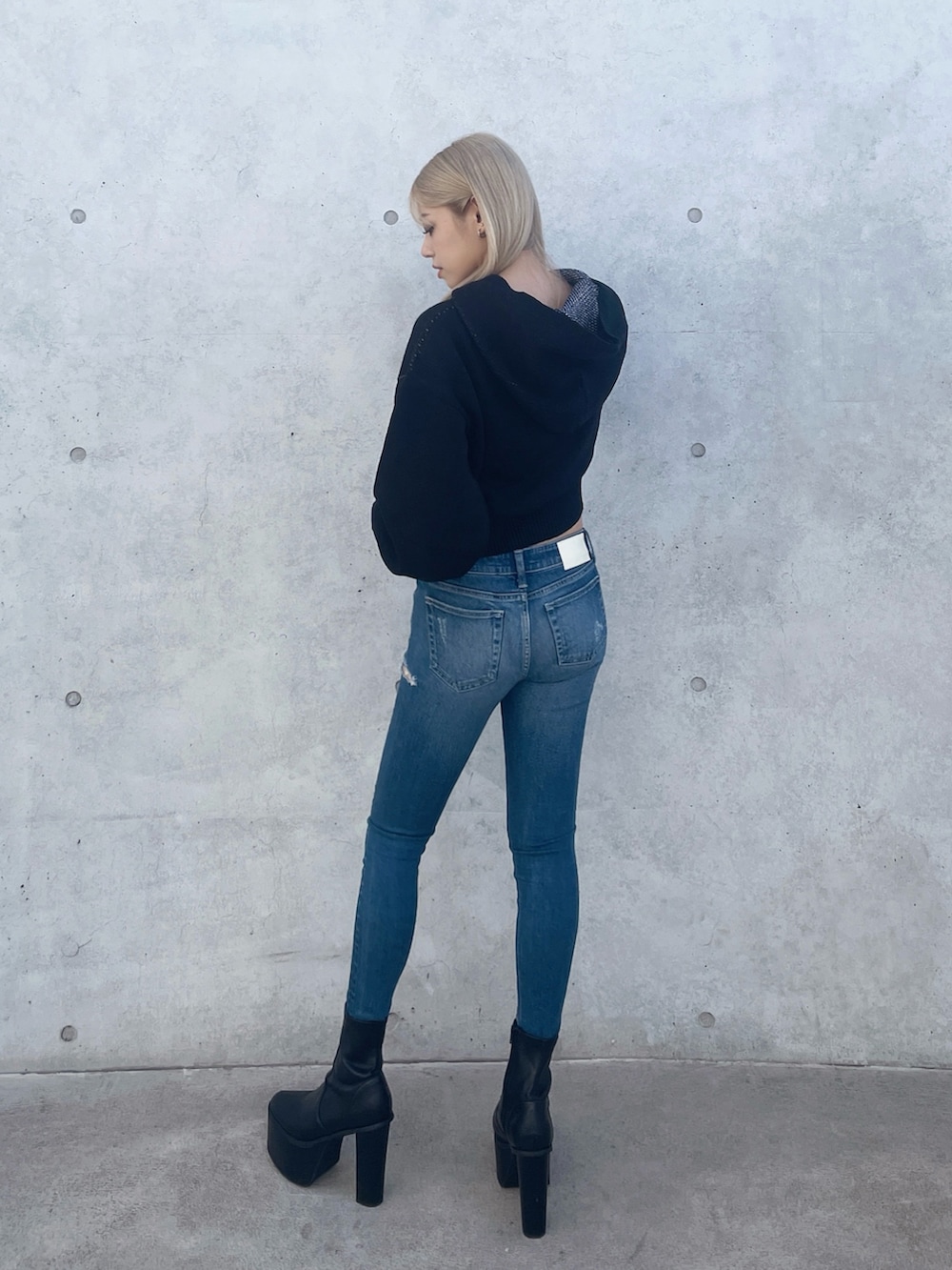 ブラック系のニット/セーター、ブルー系のデニムパンツ、ブラック系のブーツを着用したレディースの冬コーディネートの2枚目の写真