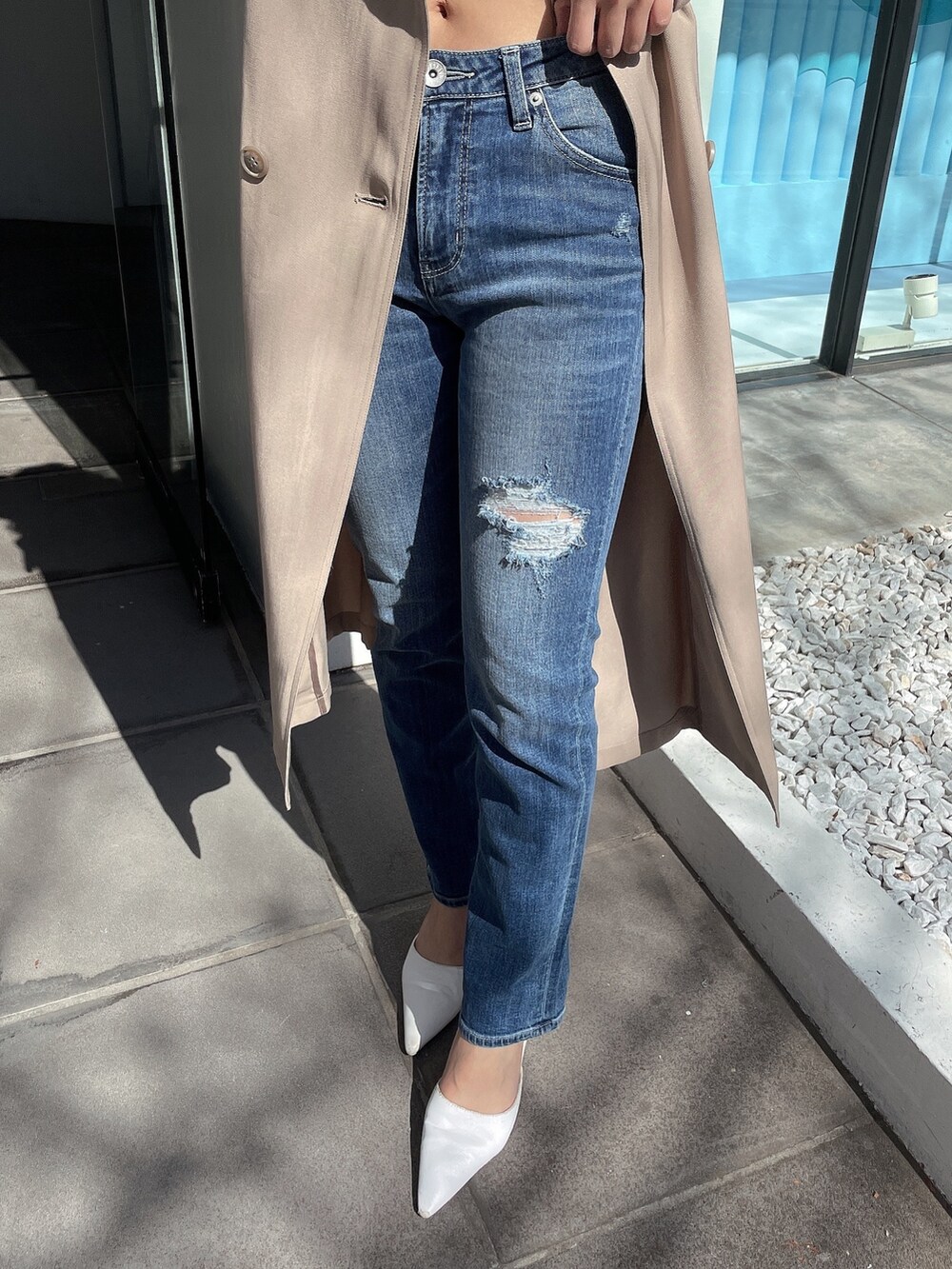 ホワイト系のニット/セーター、ベージュ系のトレンチコート、ブルー系のデニムパンツを着用したレディースの春コーディネートの7枚目の写真