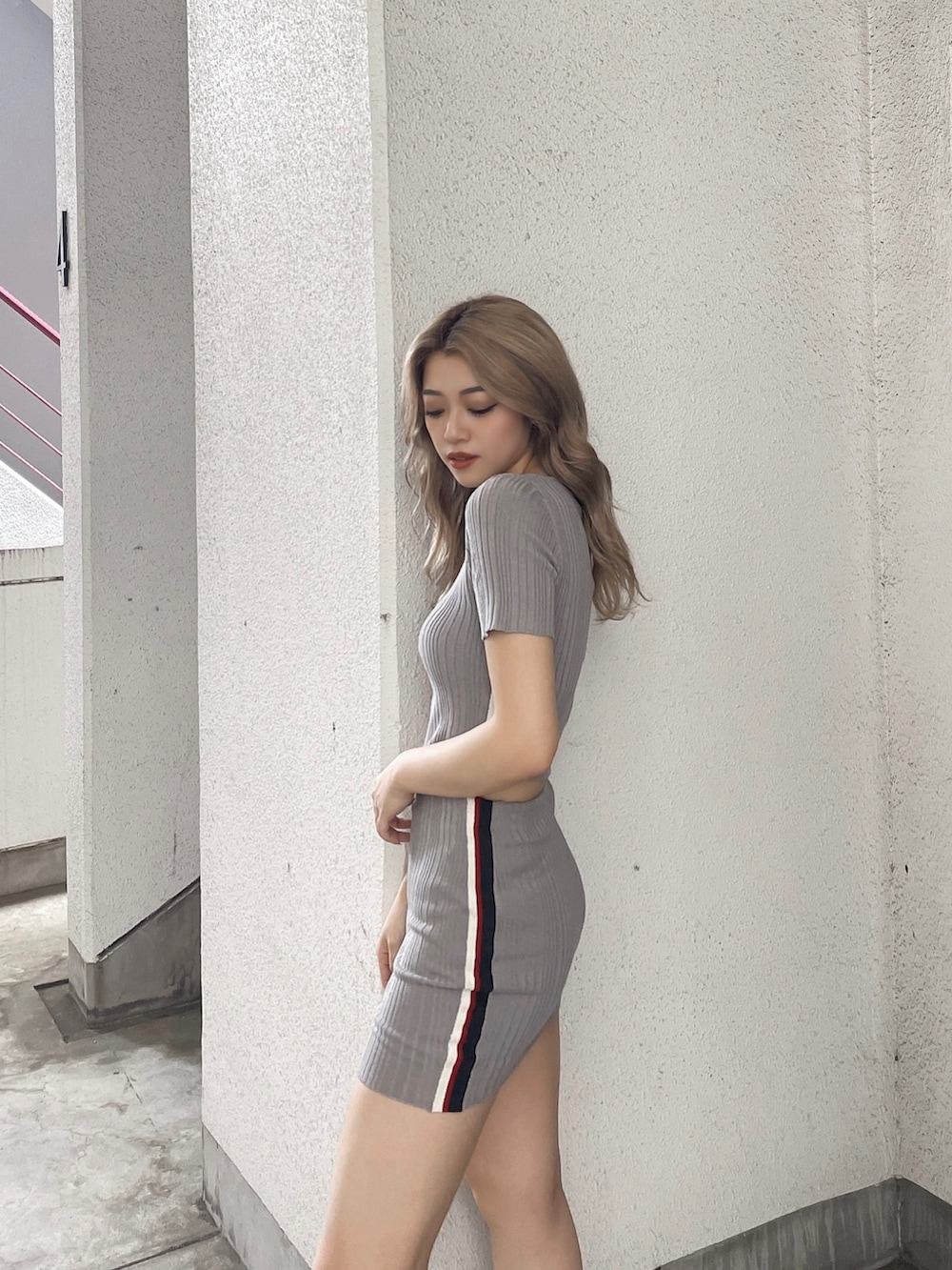 グレー系のニット/セーター、グレー系のスカート、ホワイト系のスニーカーを着用したレディースの春コーディネートの3枚目の写真