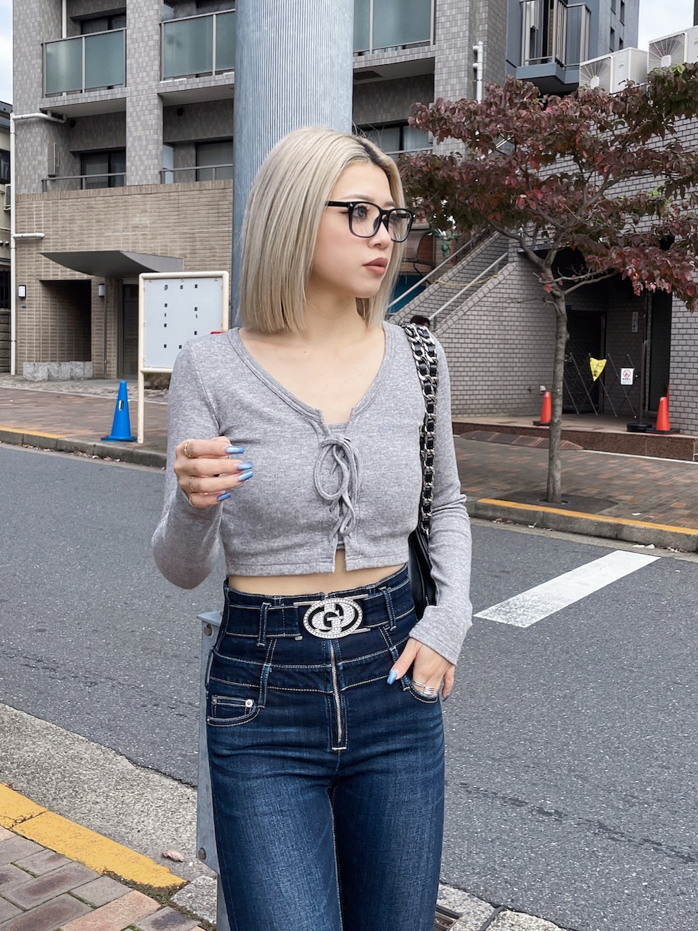 グレー系のTシャツ/カットソー、ブルー系のデニムパンツ、ブラック系のショルダーバッグを着用したレディースの秋コーディネートの3枚目の写真