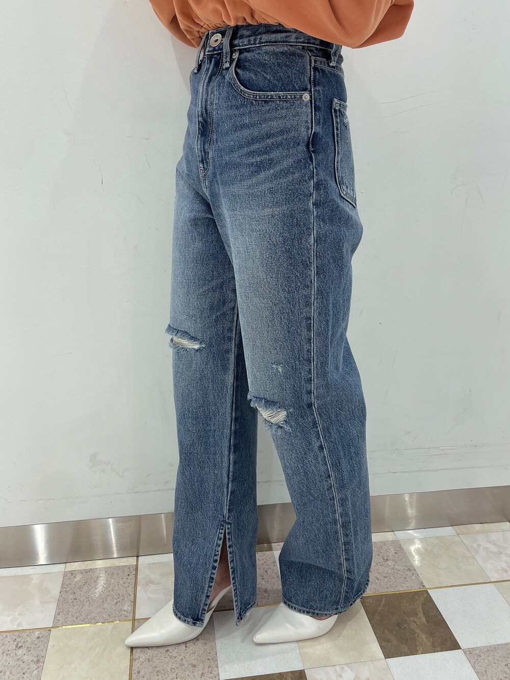 オレンジ系のTシャツ/カットソー、ブルー系のデニムパンツ、ホワイト系のパンプスを着用したレディースの冬コーディネートの7枚目の写真