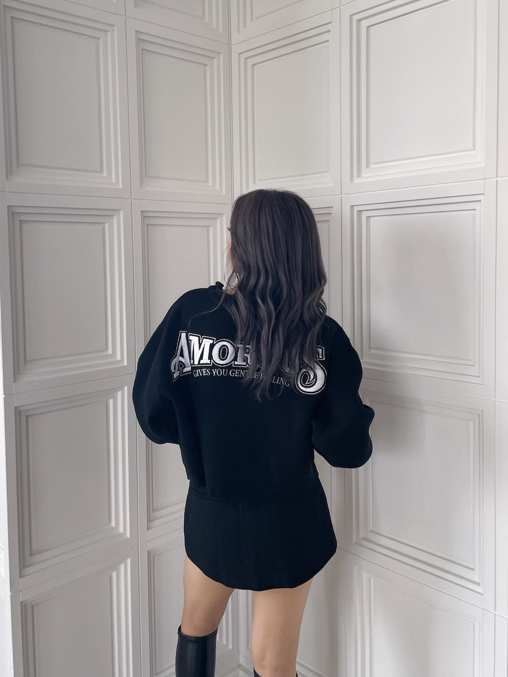 ブラック系のニット/セーター、ブラック系のスカート、ブラック系のブーツを着用したレディースの秋コーディネートの5枚目の写真