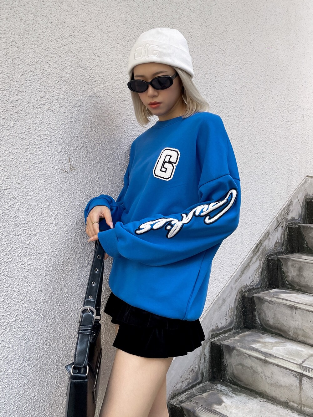 ブルー系のスウェット、ブラック系のハンドバッグ、ブラック系のブーツを着用したレディースの秋コーディネートの2枚目の写真